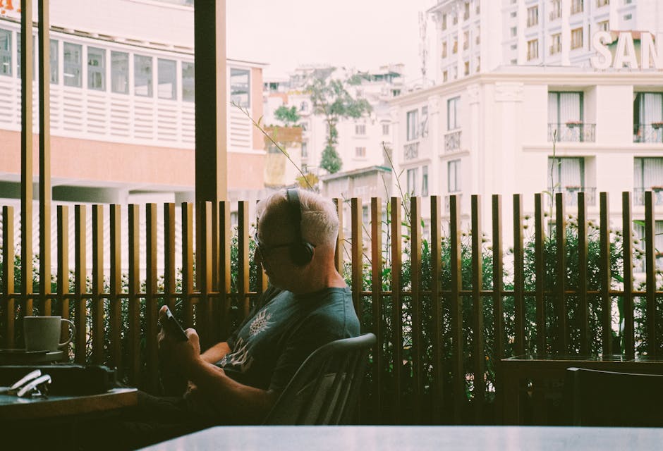 Seorang individu sedang mendengarkan musik menggunakan headphone dengan ekspresi wajah yang sangat tenang dan damai.